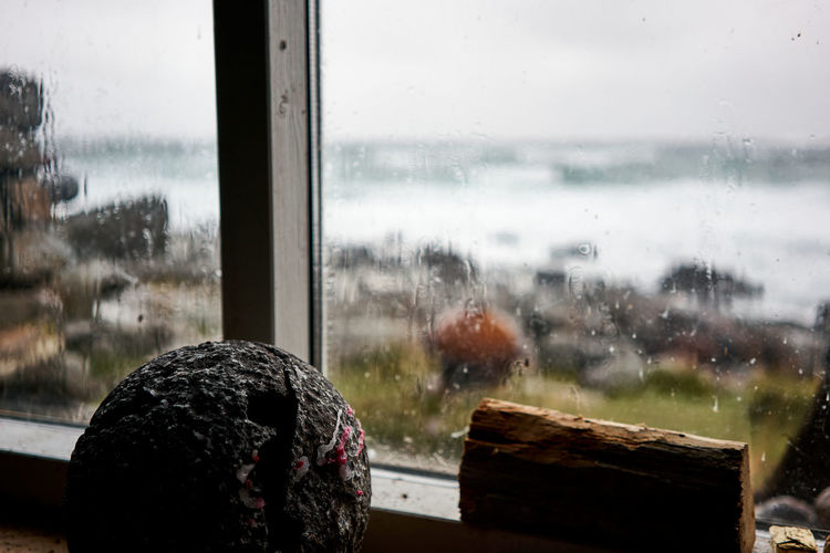  close-up view of wet window in rainy season at a cabin on to the beach and the wild arctic ocean.