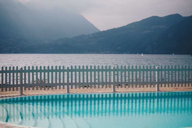 Swimming pool by lake against mountains