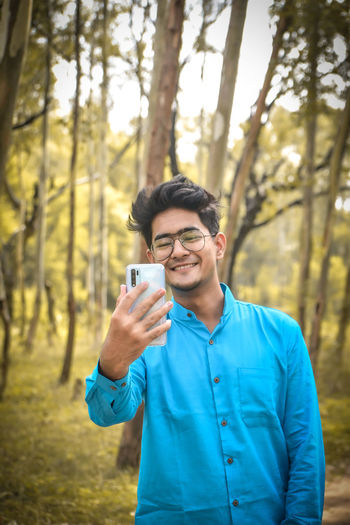 Portrait of young man using mobile phone in forest