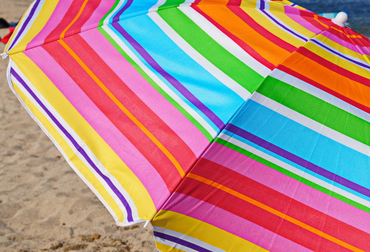 Close-up of multi colored umbrella on sand