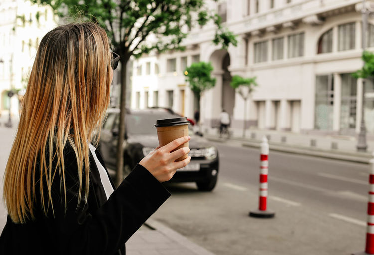 Woman holding coffee cup in city