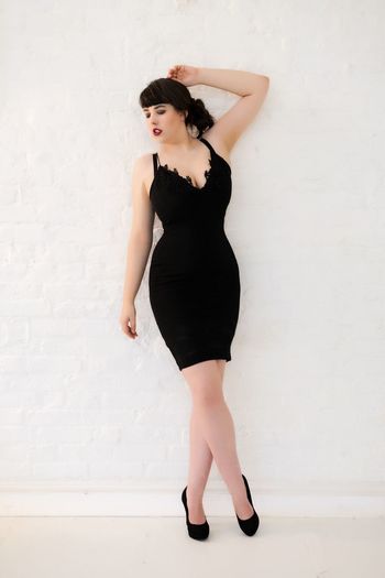 Full length portrait of woman standing against wall