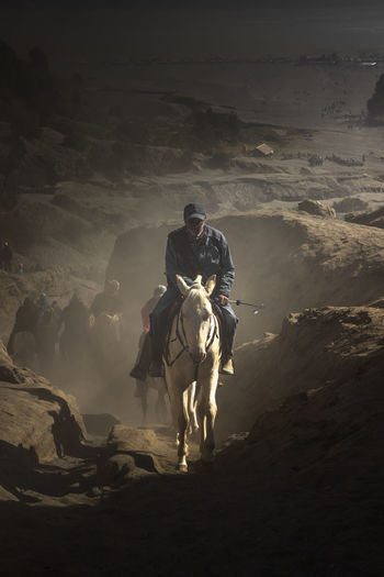Man riding horse on rocky mountain