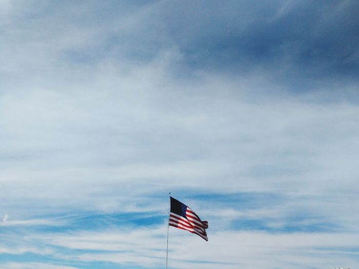 Low angle view of american flag against cloudy sky