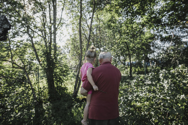 Grandfather carrying granddaughter in garden