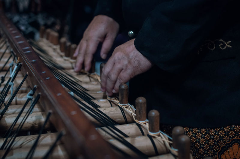 Midsection of man playing angklung 