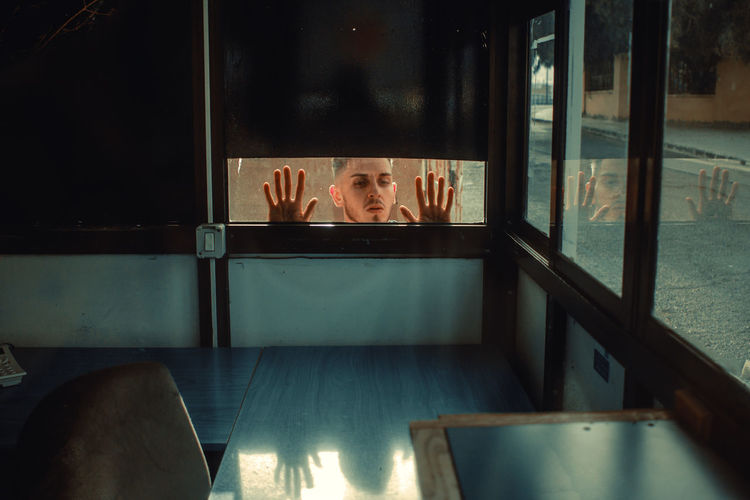 Young man peeking through window 