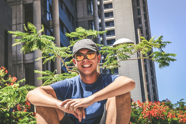 Low angle view of young man wearing sunglasses while standing against plants