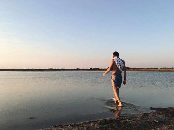 Man wading in sea against sky