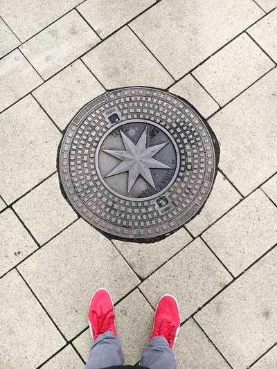 Low section of man standing by manhole on footpath