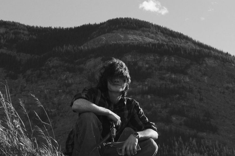 Portrait of mid adult man crouching against mountain