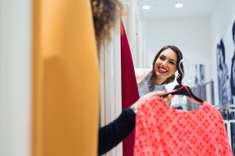 Portrait of smiling woman trying dress in shopping mall