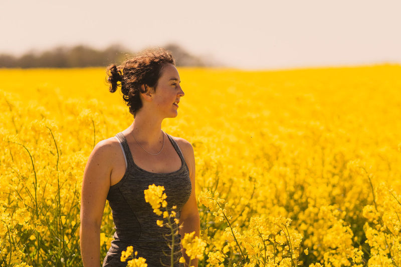 Young woman amidst yellow flowers in field