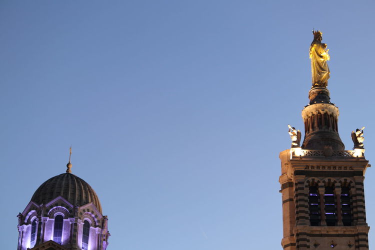 Low angle view of statue and building against clear sky during sunset