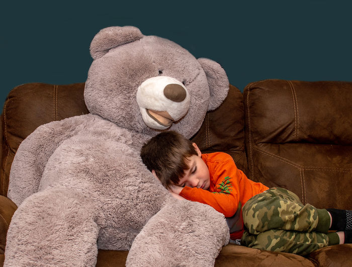 Boy sleeping on big bear