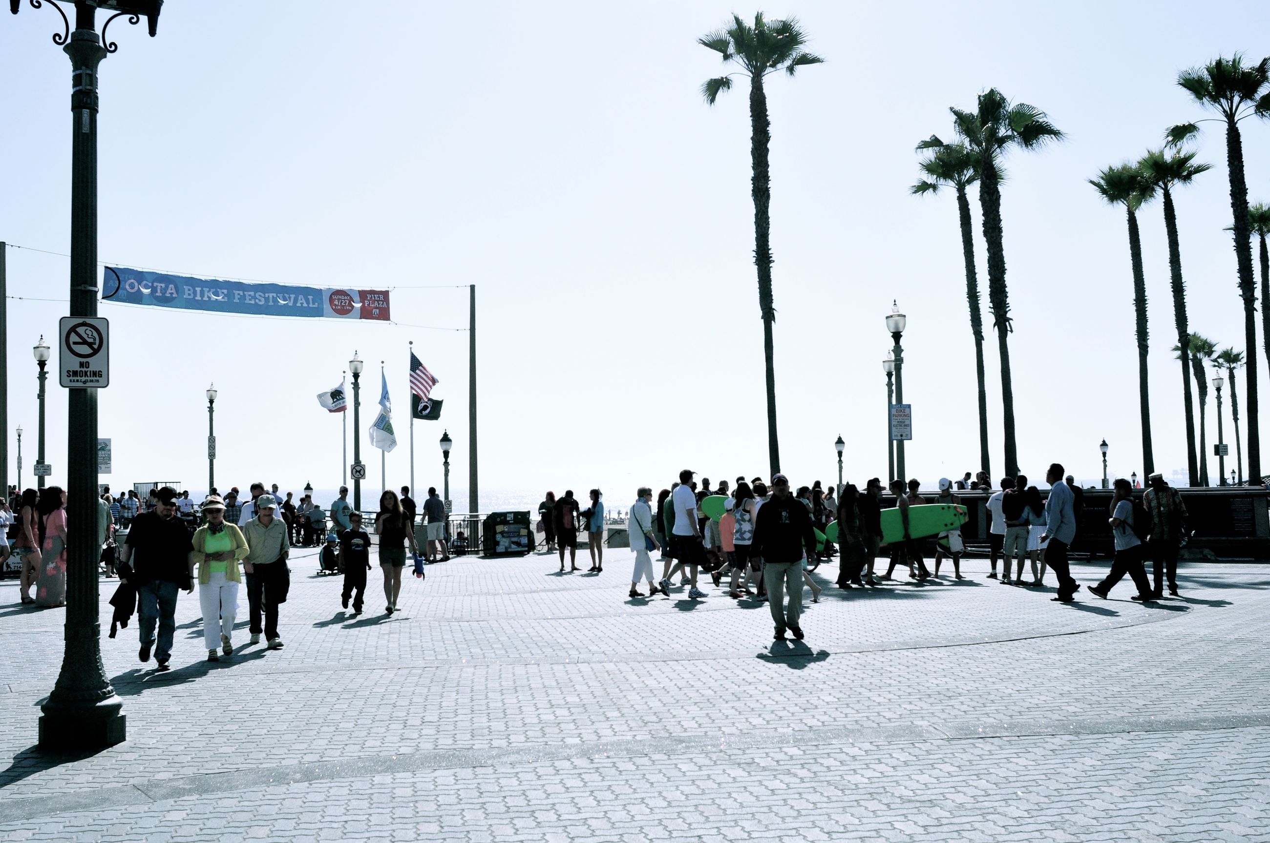 large group of people, men, person, walking, lifestyles, leisure activity, tree, sky, mixed age range, palm tree, clear sky, street light, flag, street, group of people, medium group of people, road, the way forward, day