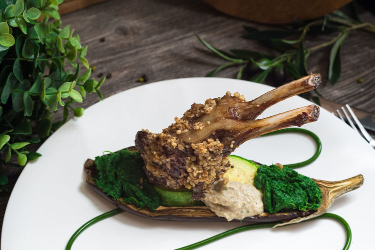 Rack of lamb in nut batter with baked vegetables. spinach paste and baked eggplant. molecular food.
