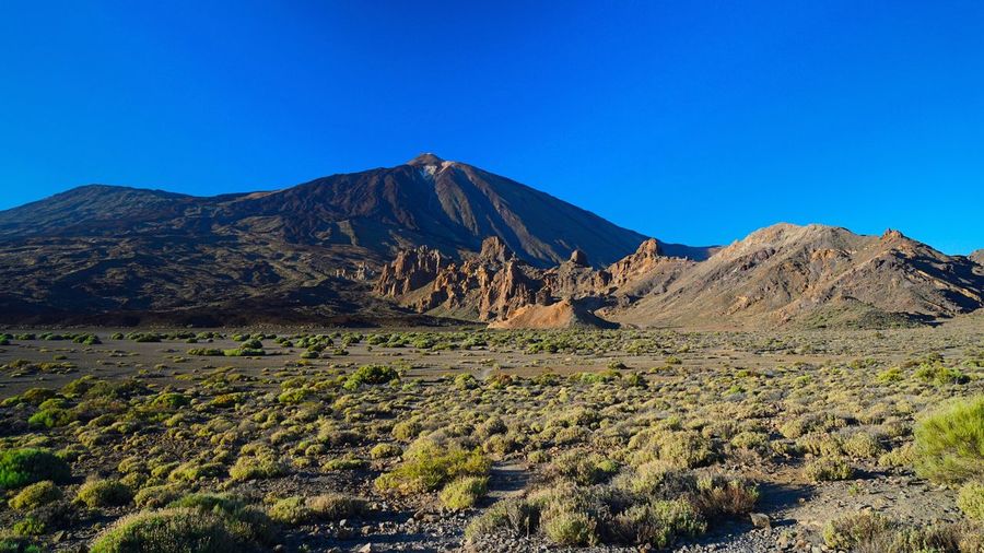 Scenic view of mountains against clear blue sky