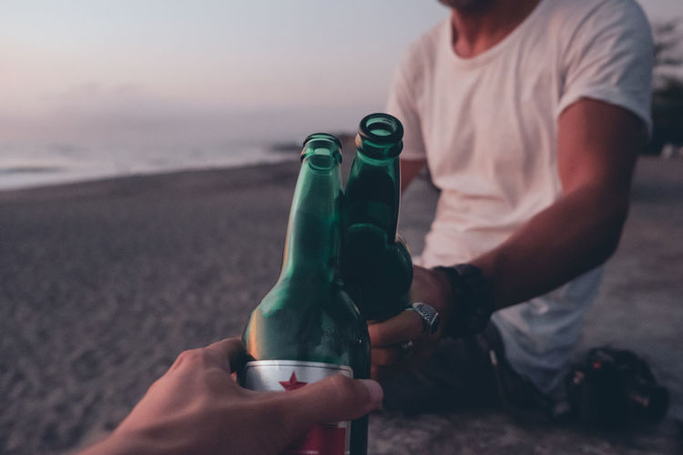 Friends toasting with beer on sunset beach