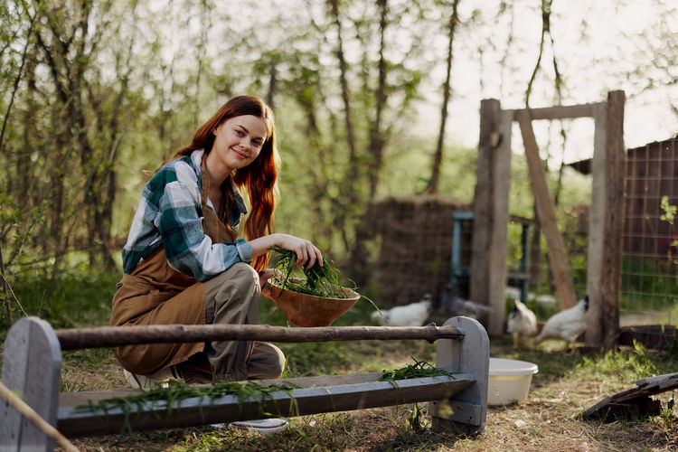Portrait of smiling woman holding bowl of leaves in farm