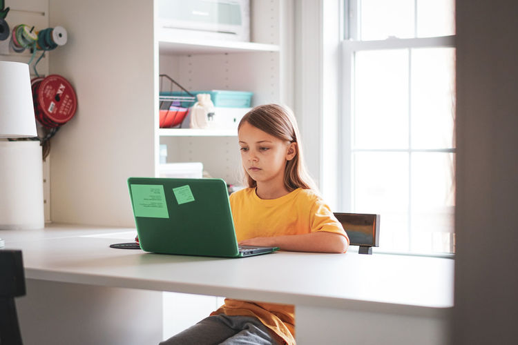 Girl studying over laptop on table at home