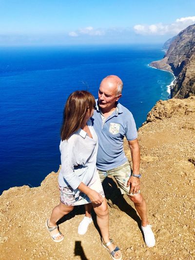 Senior couple standing on cliff by sea