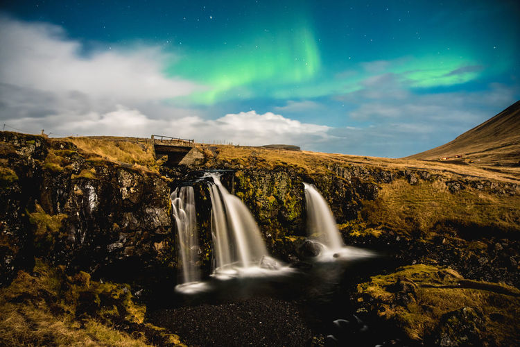 Scenic view of waterfall against night sky with aurora borealis