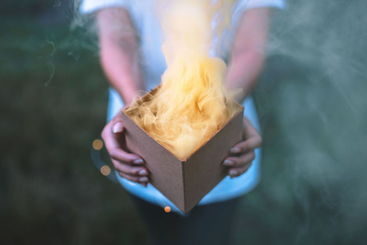 Midsection of woman holding burning box