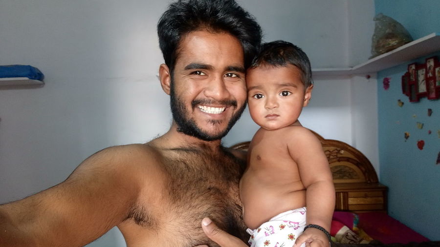 Smiling father carrying cute baby son at home
