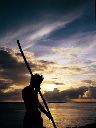 Silhouette of people in water at sunset