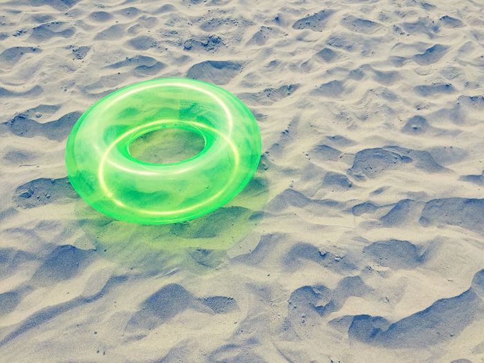 High angle view of green lifeguard ring on sand at beach