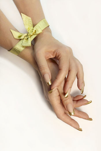 Close-up of woman holding hands over white background