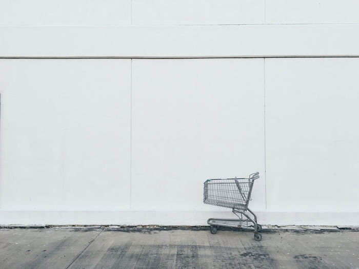 Close-up of shopping cart against white wall