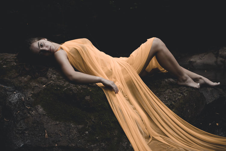 Portrait of woman lying on rock 
