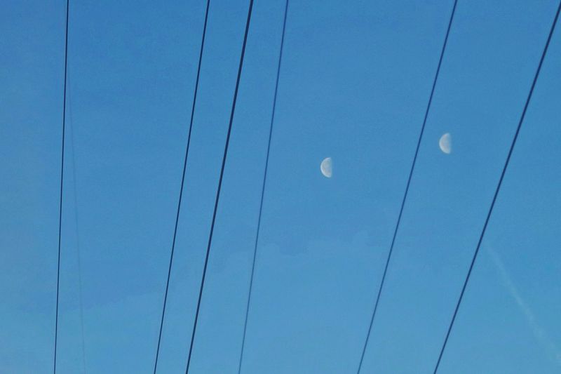 Low angle view of electricity pylon against blue sky