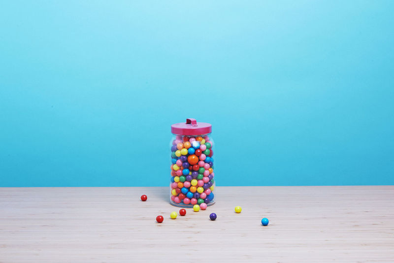 Close-up of multi colored balls on table against blue wall