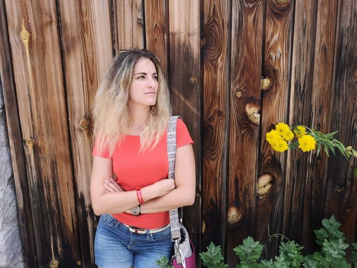 Beautiful woman standing against wooden wall