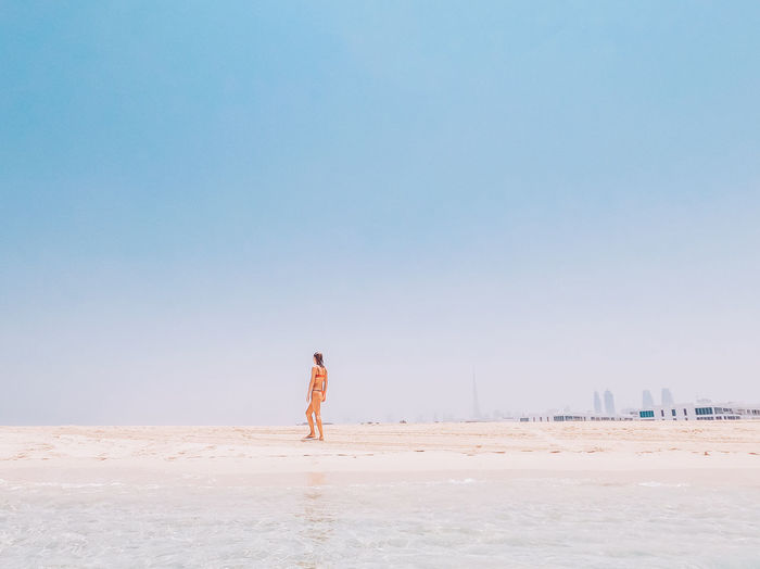 Woman standing at beach against clear sky