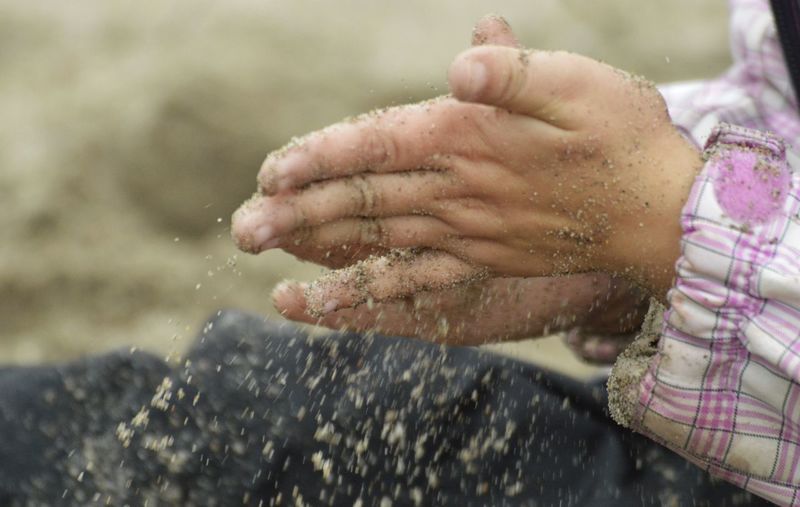 Cropped hands of child spilling sand