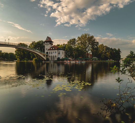 Bridge over river by buildings against sky