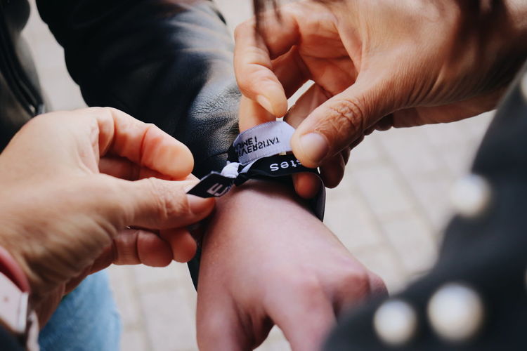 Midsection of man tying ribbon on friend hand