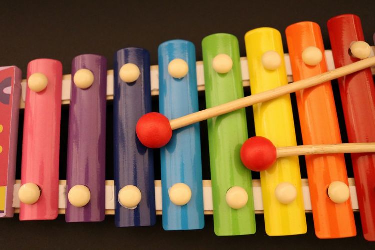 Close-up of mallets with colorful xylophone against black background