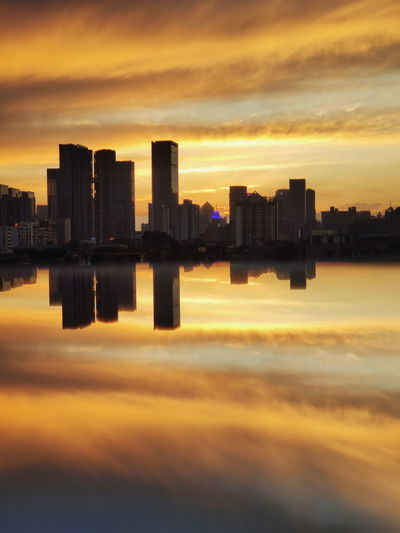 Reflection of buildings in city during sunset