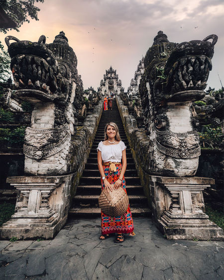 Full length portrait of woman standing by temple against sky