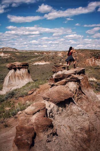Full length of young woman on rock hoodoo in badlands 