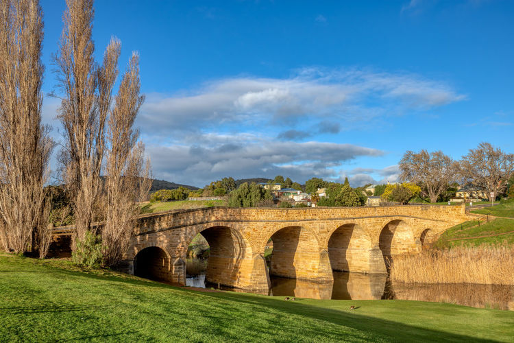 Arch bridge on field against sky