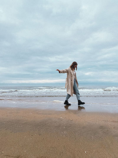 Woman standing at beach against sky and sea