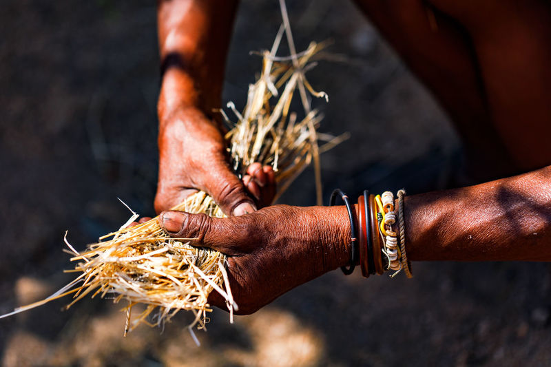 An old man with distinctive hands collects straw in namibia to make a fire
