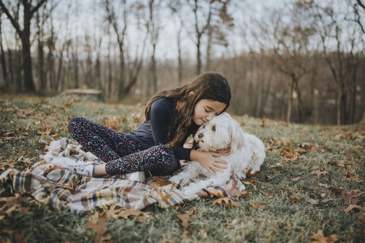 Girl embracing dog while sitting on land