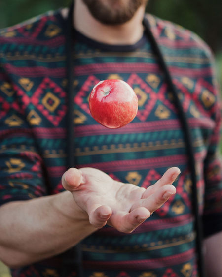 Midsection of man with apple in mid-air